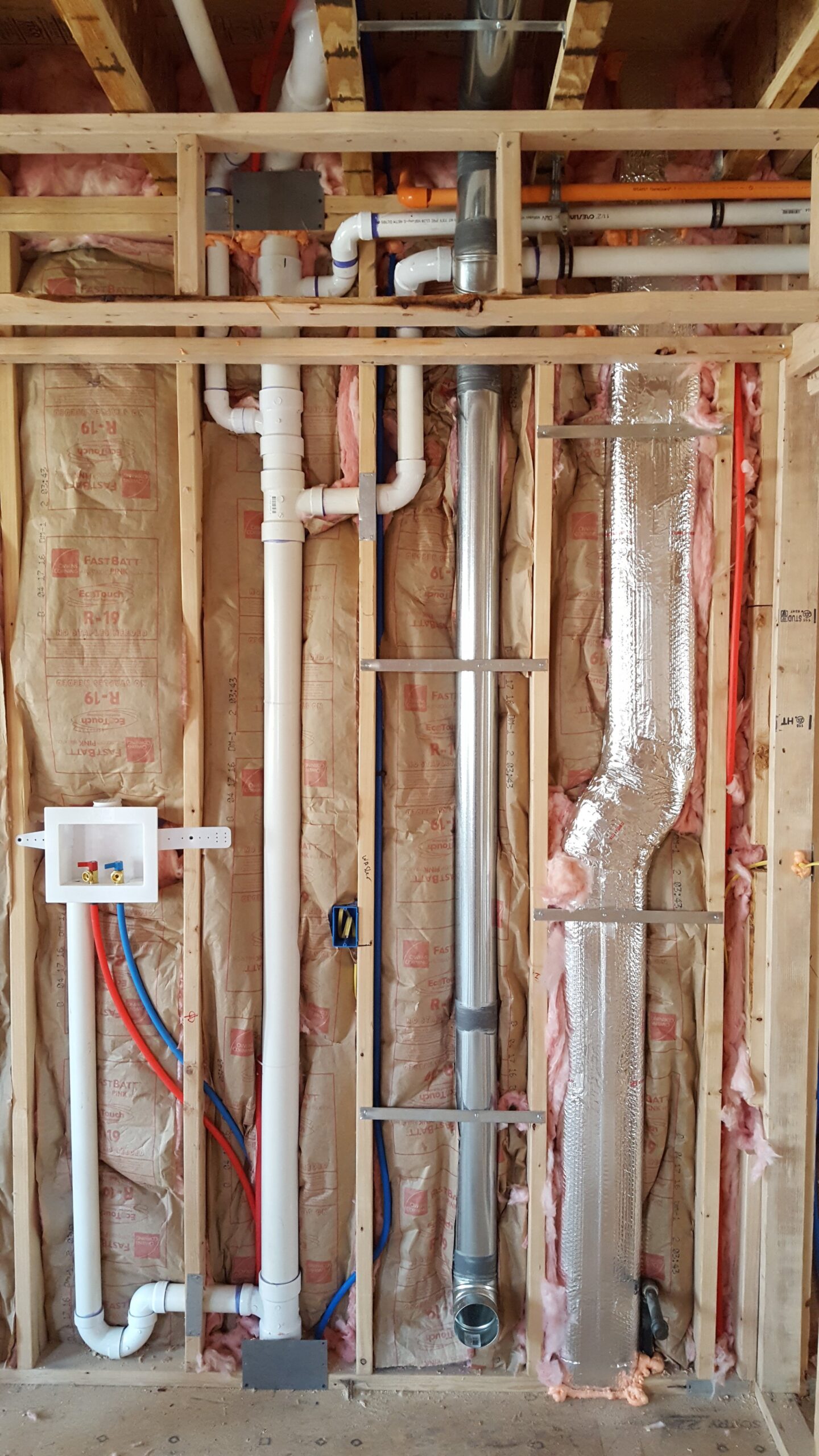 inside, after insulation and utilities go in; plumbing for the washing machine, pipes coming down from the bathroom above, sprinkler piping, venting for the dryer, and a heating duct all compete for space